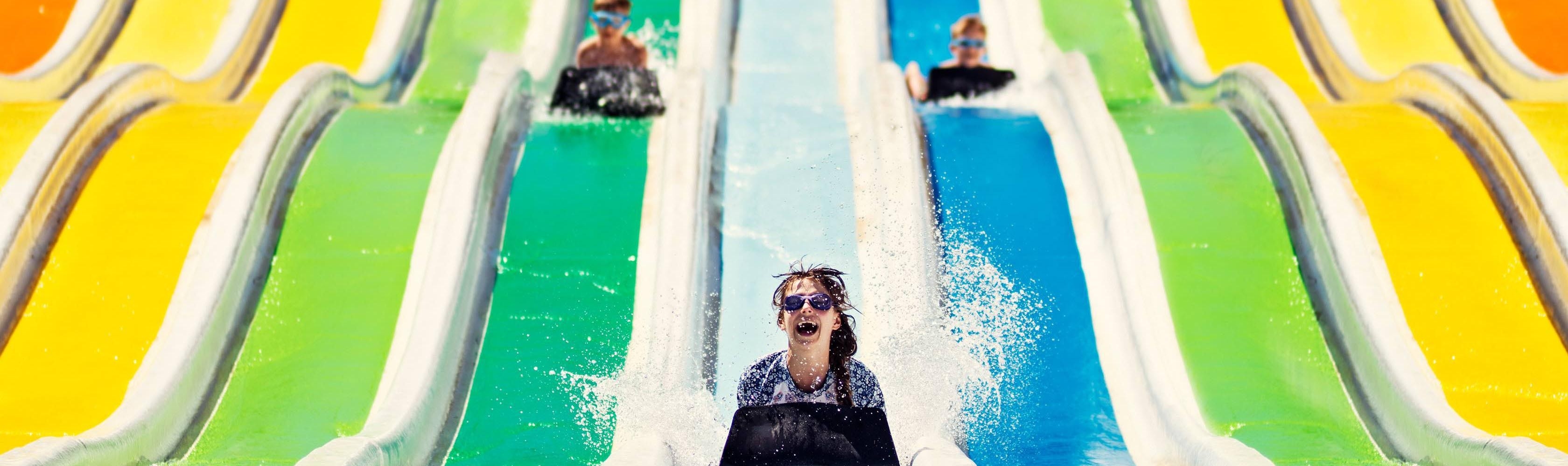 Ein Mädchen rutscht vorwärts auf dem Bauch eine Wasserrutsche im Aquapark herunter
