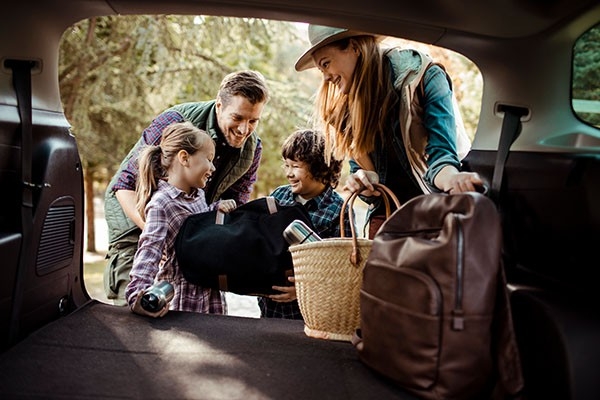 Eine Familie packt ihre Sachen in den Kofferraum vom Auto