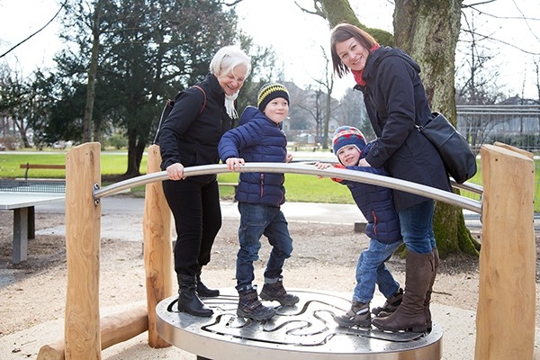Eine Familie über drei Generationen bewegt sich gemeinsam auf einem intergenerativen Spielplatz
