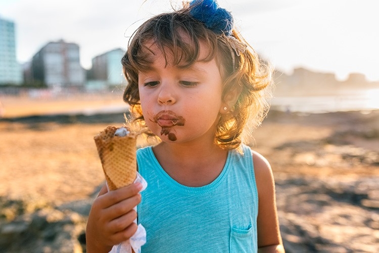 Ein kleines Mädchen geniesst ein Eis am Strand