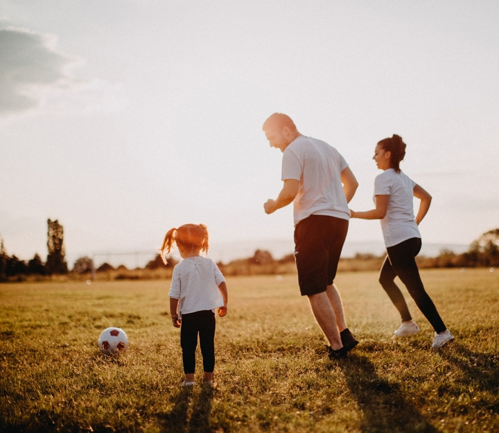Un jeune couple de parents se maintient en forme en jouant avec leur fille avec un ballon